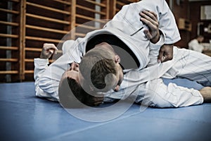 Two young males practicing judo together.