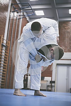 Two young males practicing judo together.