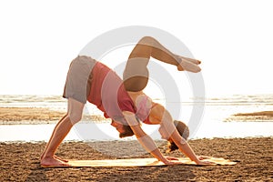 Two young man and beautiful woman on beach doing fitness yoga exercise together. Acroyoga element for strength and