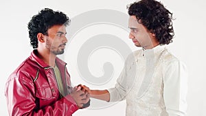 Two young man one ask forgiveness apologize his brother facing each other one in a red jacket and the other in traditional attire