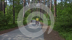 Two young men with backpacks ride bicycles along the road.