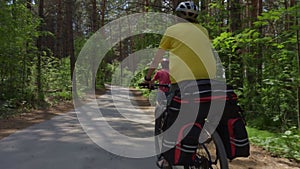 Two young men with backpacks ride bicycles along the road.