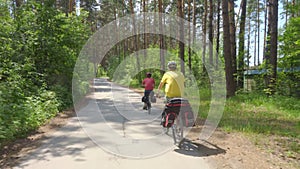 Two young men with backpacks ride bicycles along the road.