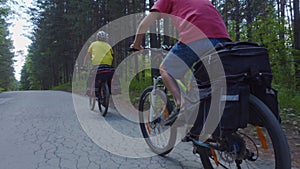 Two young men with backpacks ride bicycles along the road.