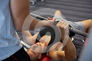 Two young men with barbell flexing muscles in gym