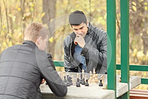 Two young men in black jackets playing chess