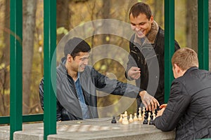 Two young men in black jackets playing chess,