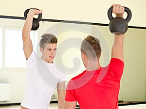 Two young men in gym working out with kettlebells photo