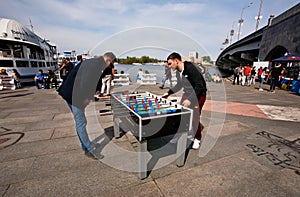 Two young men play table football on the open air street festival