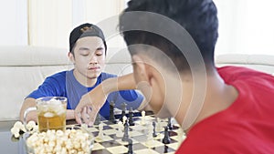 Two young men playing chess together at home