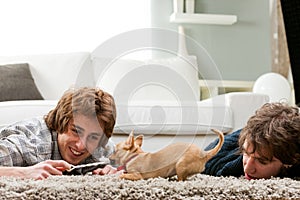 Two young men playing with a pet chihuahua