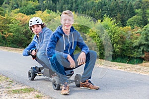 Two young men sitting on mountainboard in nature