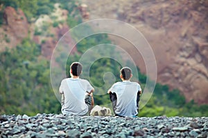 Two young men sitting on rocky cliff