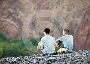 Two young men sitting on rocky cliff