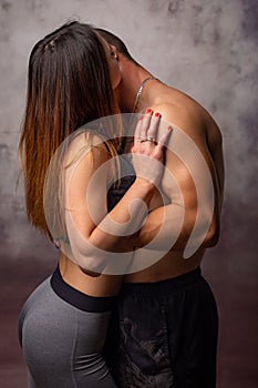 Two young men sporting physique kiss each other, turning away