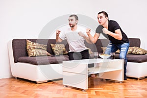 Two young men watching a football match on tv. Sport fans