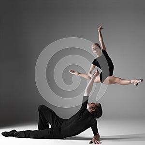 Two young modern ballet dancers on gray studio