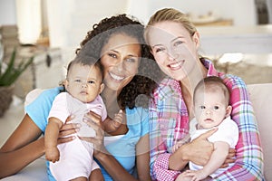 Two Young Mothers On Sofa At Home