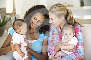 Two Young Mothers On Sofa At Home