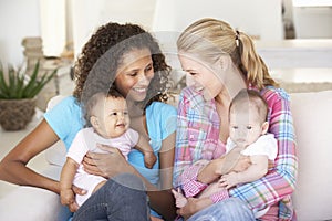 Two Young Mothers On Sofa At Home