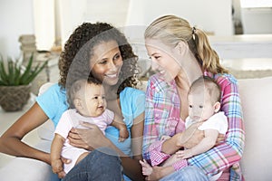 Two Young Mothers On Sofa At Home