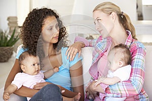 Two Young Mothers On Sofa At Home