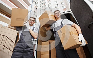 Two young movers are at their work near their car in a courtyard