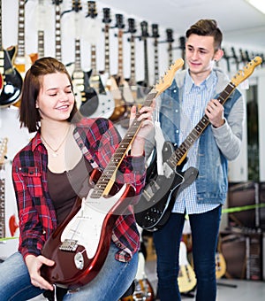 Two young people customers examining electric guitars