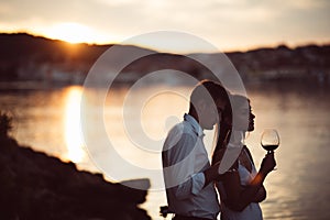 Two young people enjoying a glass of red wine in the sunset on the seaside.Healthy glass od homemade red wine,Mediterranean