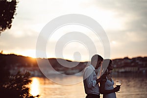 Two young people enjoying a glass of red wine in the sunset on the seaside.Healthy glass od homemade red wine,Mediterranean