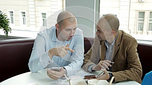 Two young people at lunch in a cafe drinking coffee and eating noodles discussing business. Work, food, phone