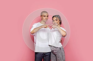 Two young people making heart. Love concept. Ypung man and woman on pink background