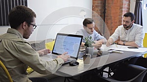 Two young people view sheet of paper with drawing in office.