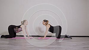 Two young pregnant women do fitness gymnastics in a sports club