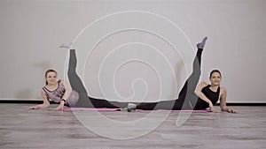 Two young pregnant women do fitness gymnastics in a sports club