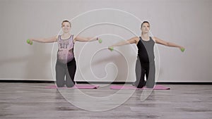 Two young pregnant women do fitness gymnastics in a sports club