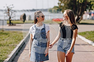 Two young pretty girls on a walk in the park. a sunny summer day, joy and friendships