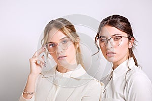 Two young pretty ladies isolated wearing reading glasses