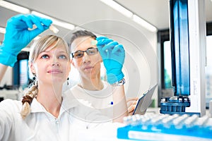 Two young researchers carrying out experiments in a lab photo