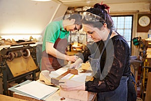 Two young shoemakers preparing shoe lasts in a workshop