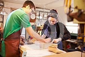 Two young shoemakers preparing shoe lasts in a workshop