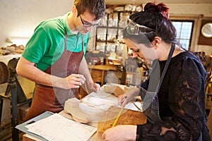 Two young shoemakers preparing shoe lasts in a workshop