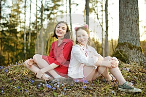 Two young sisters having fun during a hike in the woods on beautiful sunny spring day. Active family leisure with kids