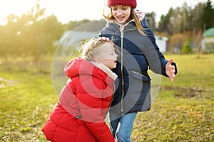 Two young sisters having fun together on beautiful spring day. Active family leisure with kids. Family fun outdoors