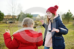 Two young sisters having fun together on beautiful spring day. Active family leisure with kids. Family fun outdoors