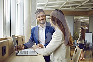 Business people man and woman discussing work project in office sitting with laptop.