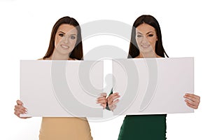 Two young smiling women holding two pieces of blank paper