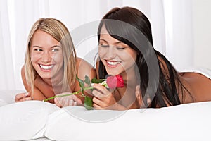 Two young smiling women naked in bed