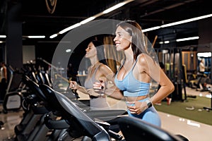 Two Young sports women are working out in gym. Doing cardio training on treadmill. Running on treadmill.