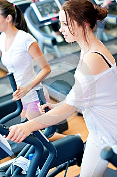 Two young sporty women run on machine